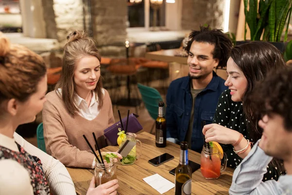 Amigos con bebidas, tarjeta de crédito y factura en el bar — Foto de Stock