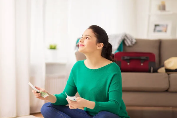 Gelukkige vrouw met geld en reizen tas thuis — Stockfoto