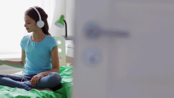 スマート フォンとヘッドフォンを家庭で幸せな女の子 — ストック動画