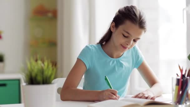 Happy girl with book writing to notebook at home — Stock Video