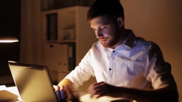 Man met laptop en smartphone bij nacht kantoor — Stockvideo