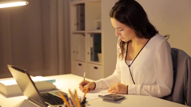 Mulher com calculadora e papéis no escritório da noite — Vídeo de Stock