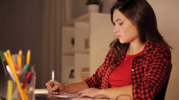 Студентська дівчина з ноутбуком і блокнотом вдома — стокове відео
