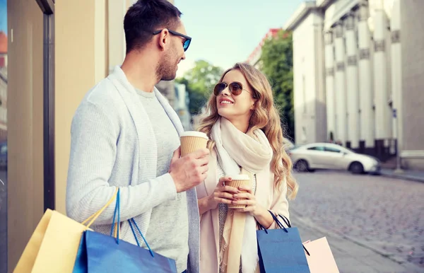 Glückliches Paar mit Einkaufstaschen und Kaffee in der Stadt — Stockfoto