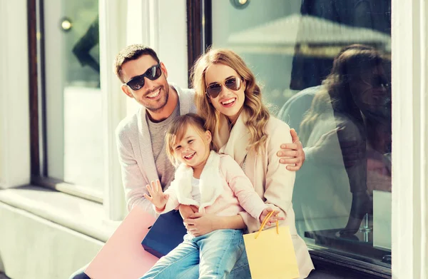 Família feliz com criança e sacos de compras na cidade — Fotografia de Stock