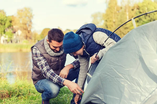 Happy father and son setting up tent outdoors — Stock Photo, Image