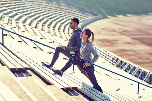 Couple stretching leg on stands of stadium — Stock Photo, Image