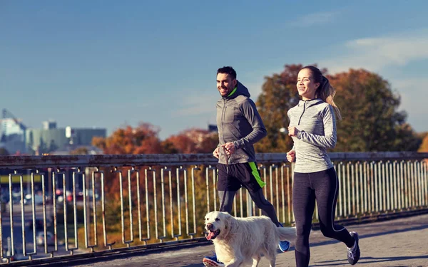 Feliz pareja con perro corriendo al aire libre — Foto de Stock