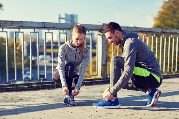 Smiling couple tying shoelaces outdoors — Stock Photo, Image