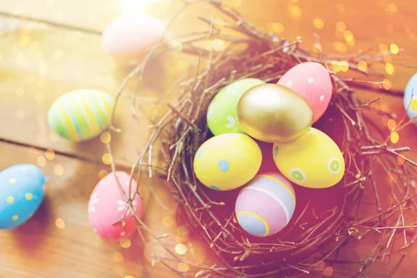 Close up of colored easter eggs in nest on wood — Stock Photo, Image