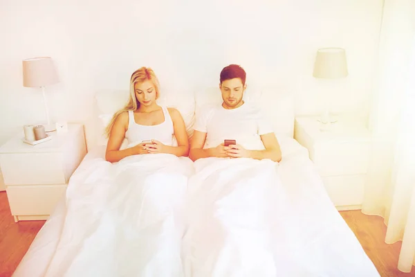 Casal com smartphones na cama — Fotografia de Stock