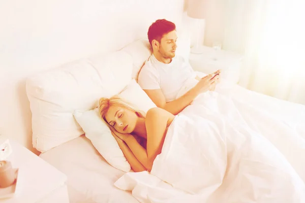 Uomo sms messaggio mentre la donna dorme a letto — Foto Stock