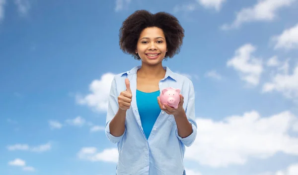 Gelukkige vrouw met spaarvarken duimen opdagen — Stockfoto