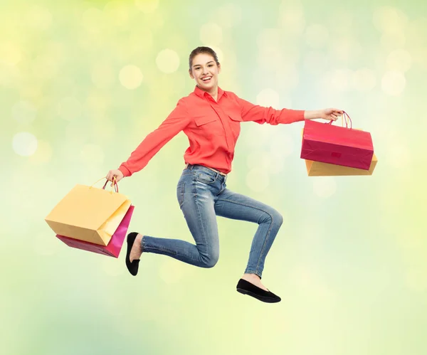 Sourire jeune femme avec des sacs à provisions sautant — Photo