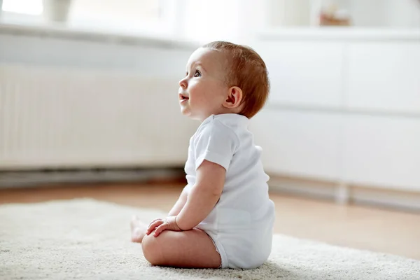 Glad liten pojke eller flicka sitter på golvet hemma — Stockfoto