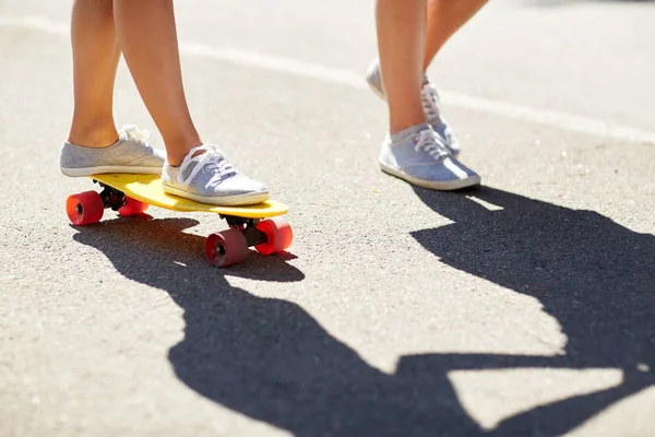 Pies de pareja adolescente montando monopatín en carretera — Foto de Stock