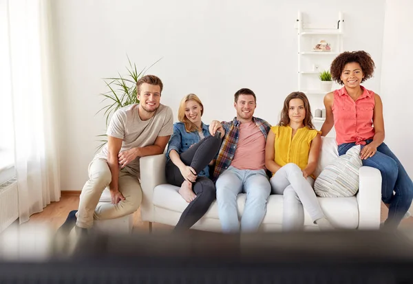 Amici felici con telecomando guardando la tv a casa — Foto Stock