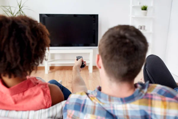 Amigos felizes com controle remoto assistindo tv em casa — Fotografia de Stock