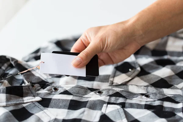 Close up of hand holding checkered shirt price tag — Stock Photo, Image