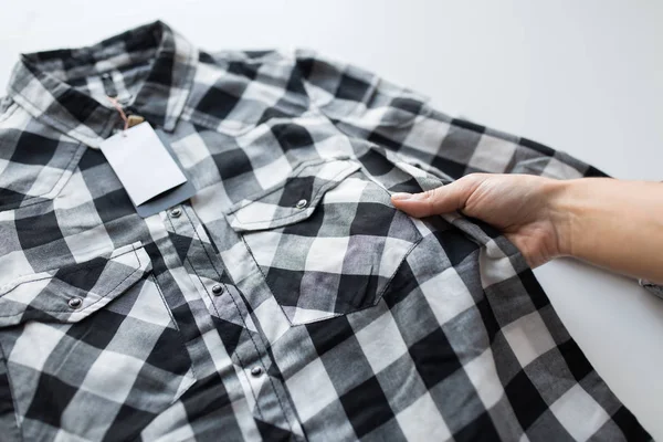 Primer plano de la mano y la camisa con etiqueta de precio — Foto de Stock