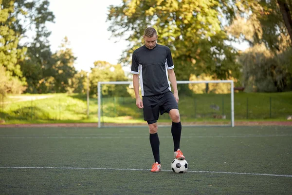 Jogador de futebol jogando com bola no campo de futebol — Fotografia de Stock