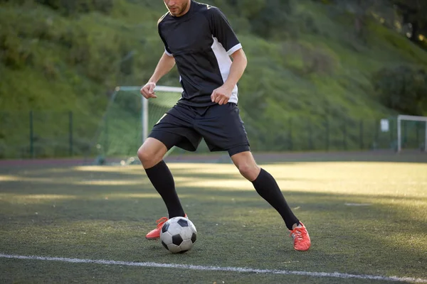 Jogador de futebol jogando com bola no campo de futebol — Fotografia de Stock