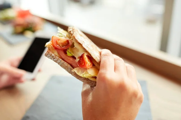 Mano con sándwich de salmón panini en el restaurante —  Fotos de Stock