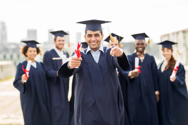 Estudiante feliz con diploma señalándote con el dedo — Foto de Stock