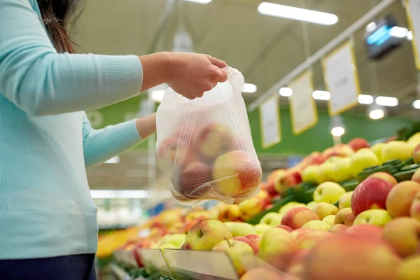 Vrouw met tas kopen van appels in supermarkt — Stockfoto