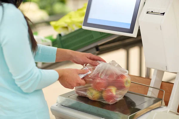Žena o hmotnosti jablka v měřítku v obchodu s potravinami — Stock fotografie