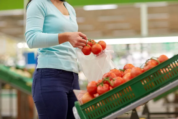 Vrouw met tas kopen van tomaten in supermarkt — Stockfoto