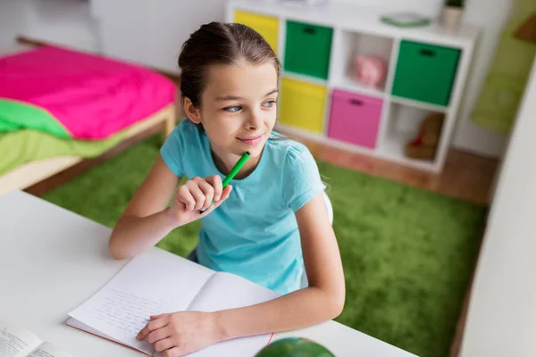 Ragazza felice con libro che scrive a taccuino a casa — Foto Stock