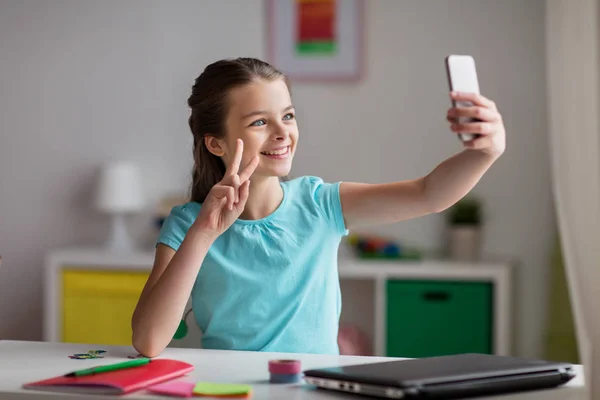 Menina feliz com smartphone levando selfie em casa — Fotografia de Stock
