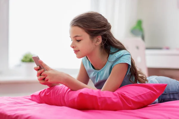 Chica sonriente mensajes de texto en el teléfono inteligente en casa —  Fotos de Stock