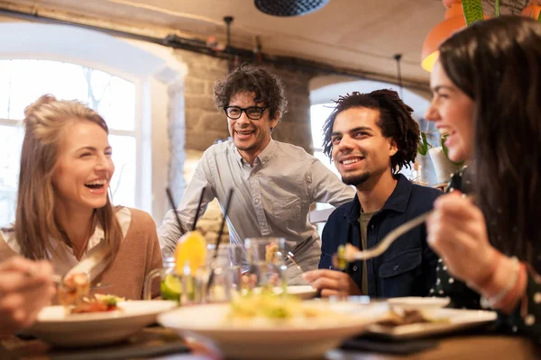Happy přátelé, jídlo a pití v restauraci — Stock fotografie