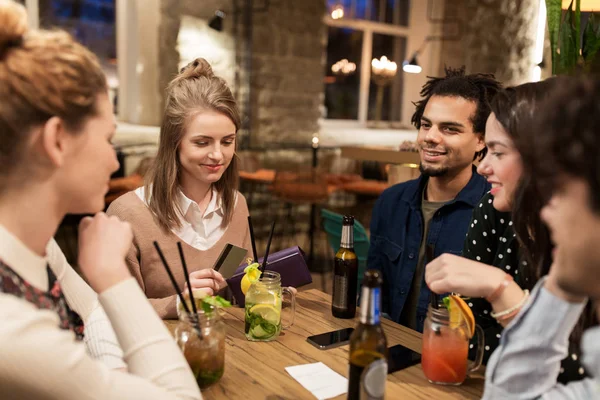 Friends with drinks, credit card and bill at bar — Stock Photo, Image