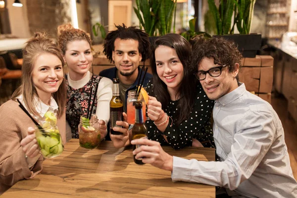Happy friends with drinks at bar or cafe — Stock Photo, Image
