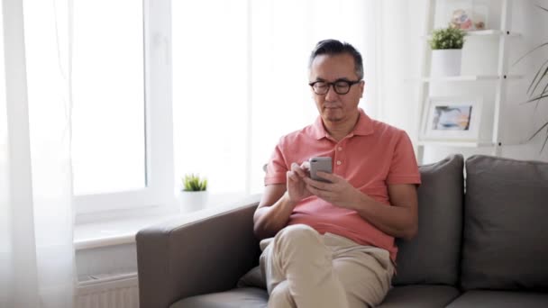 Man with smartphone sitting on sofa at home — Stock Video