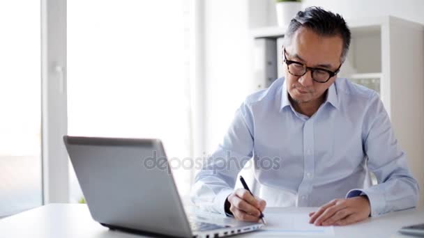 Homme d'affaires avec ordinateur portable et papiers au bureau — Video