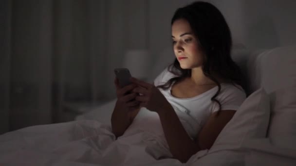 Kadın yatakta uyuyacak smartphone ile — Stok video