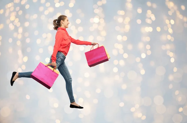 Usměvavá mladá žena s nákupní tašky běží — Stock fotografie