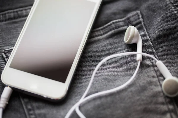 Smartphone e fones de ouvido no bolso de ganga ou jeans — Fotografia de Stock