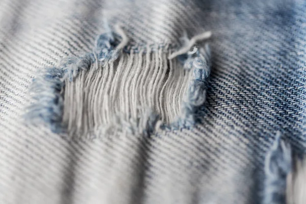 Nahaufnahme des Lochs auf schäbiger Jeans- oder Jeanskleidung — Stockfoto