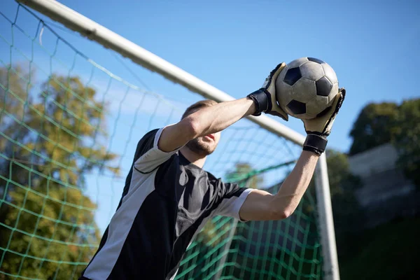 Goleiro com bola no gol de futebol em campo — Fotografia de Stock