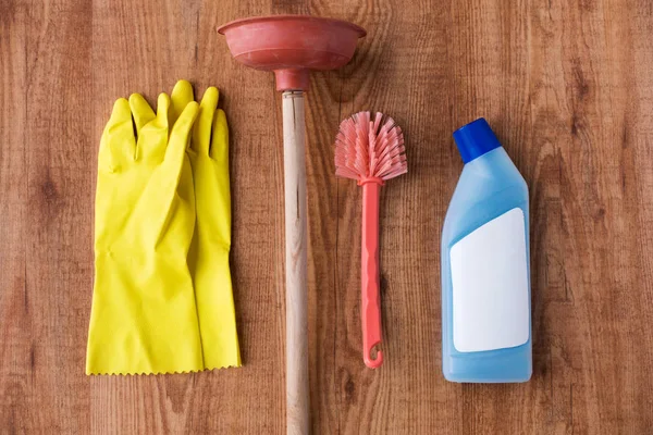 Plunger dengan barang-barang pembersih di latar belakang kayu — Stok Foto