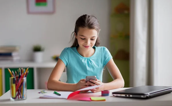 Girl with smartphone distracting from homework — Stock Photo, Image