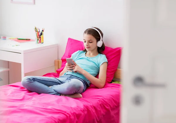 Flicka i hörlurar och smartphone hemma — Stockfoto