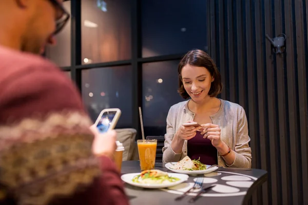 Happy couple with smartphones at vegan restaurant — Stock Photo, Image