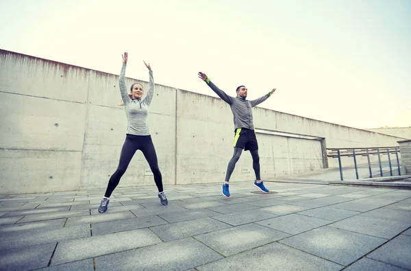 Happy man and woman jumping outdoors — Stock Photo, Image