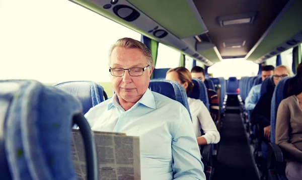 Homem sênior feliz lendo jornal em ônibus de viagem — Fotografia de Stock